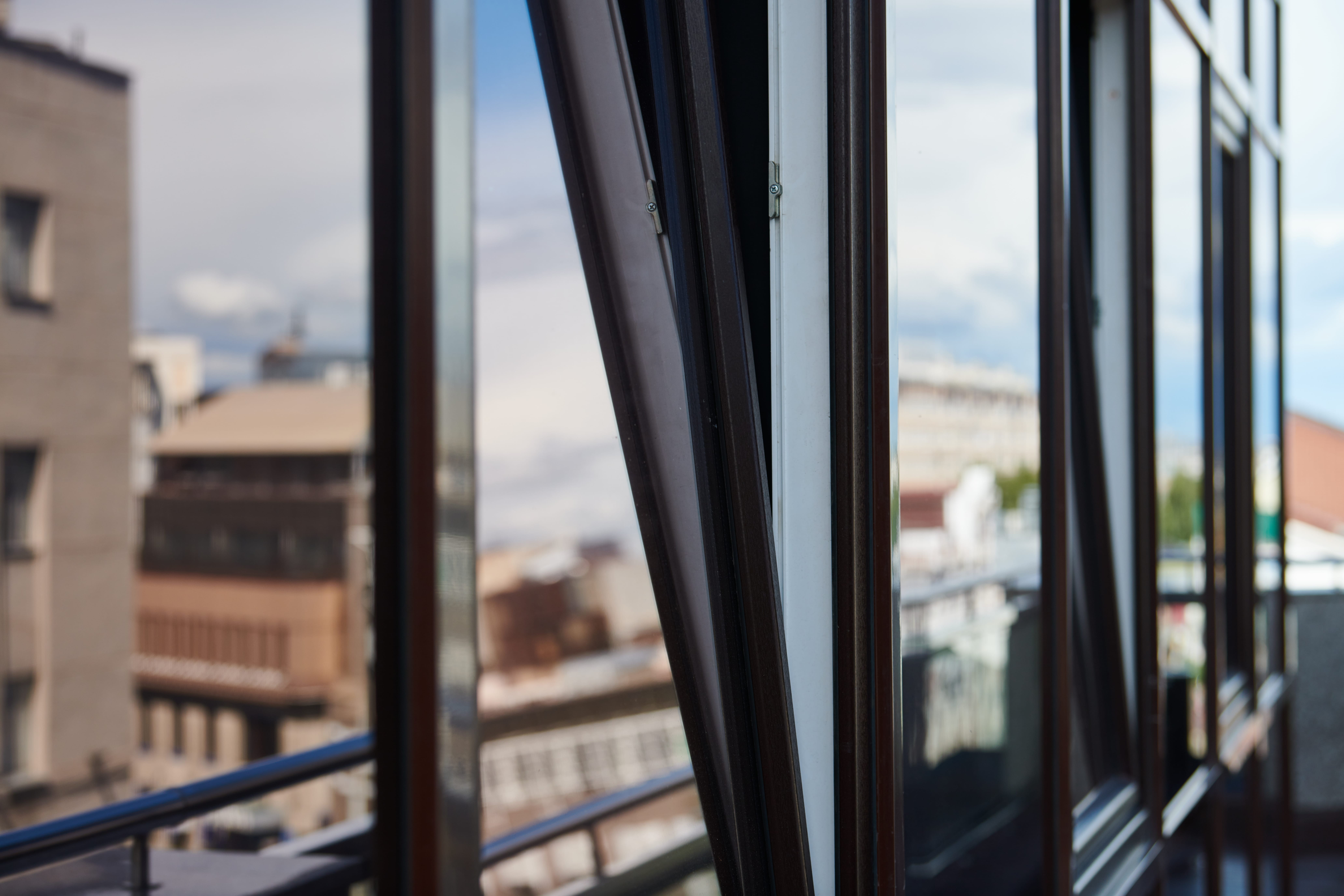 Open aluminium BTO window with slim black frames, providing natural ventilation and overlooking an urban residential view