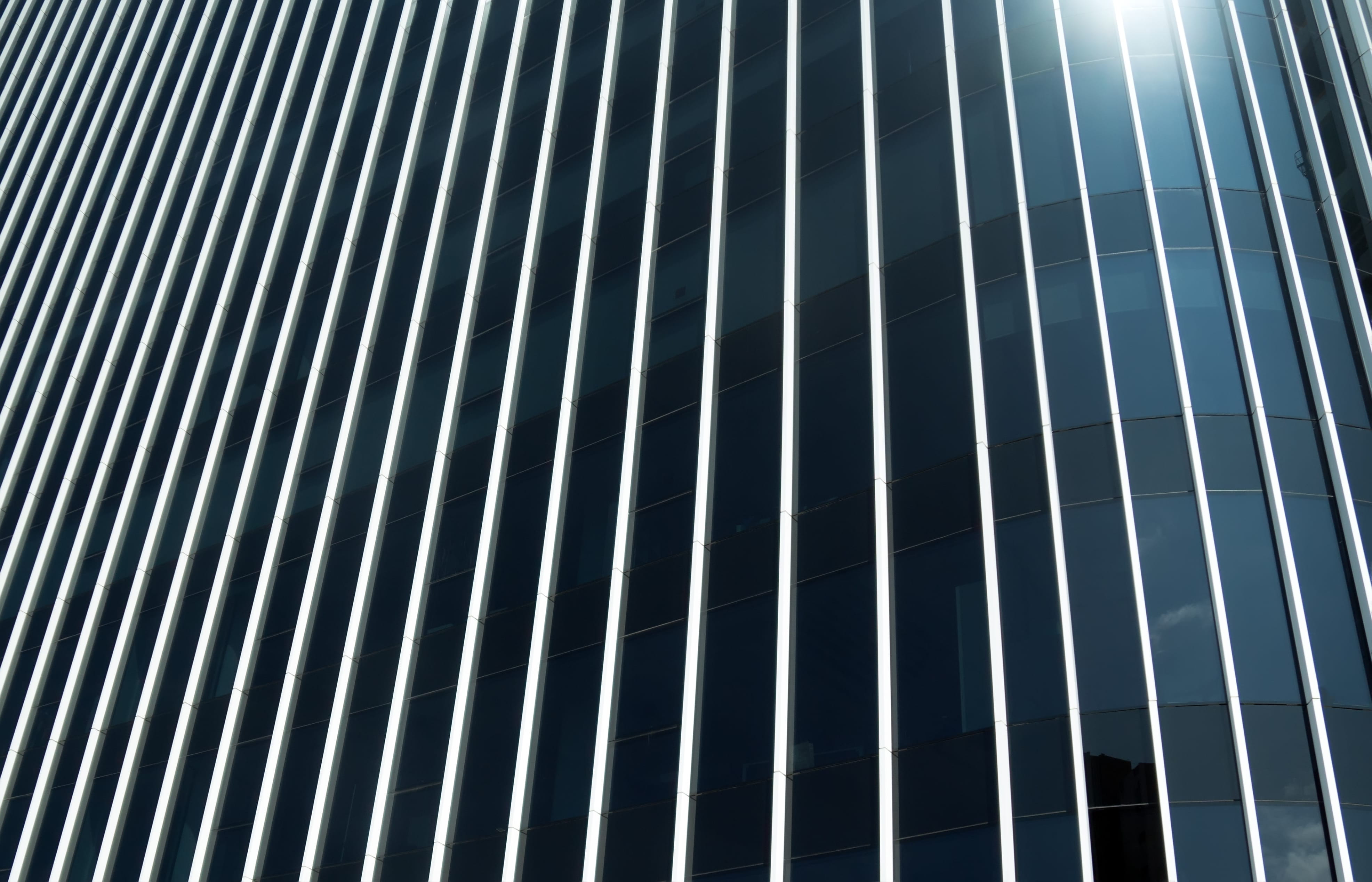 Modern glass building façade with vertical lines resembling an invisible grille design, showcasing a sleek and minimalist architectural appearance.